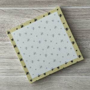 A square sticky notepad with a pattern of bees and a yellow border