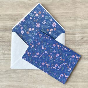 A card with a blue floral pattern with a matching envelope on a table