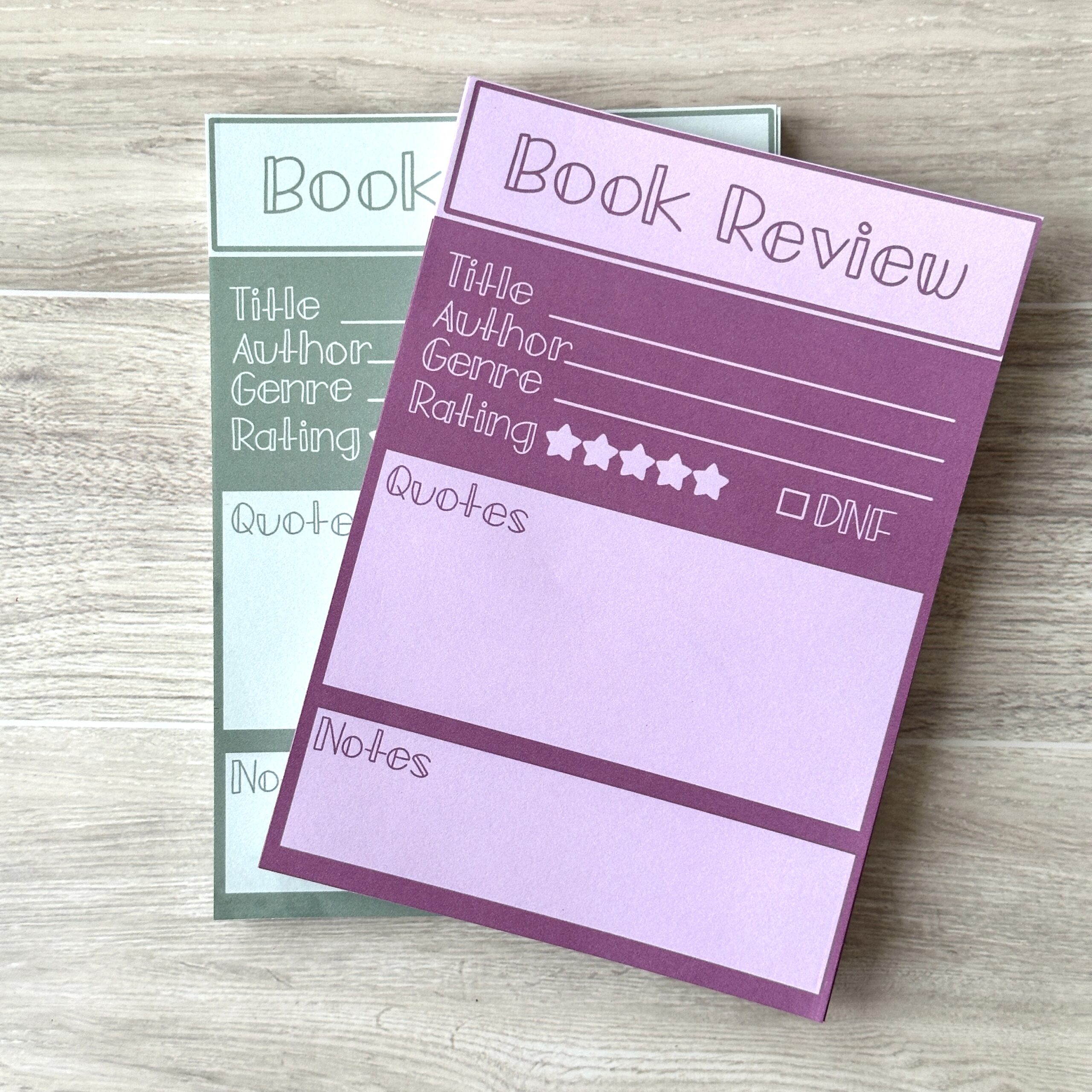 2 book review paper pads in purple and blue sits on a table with a white pen
