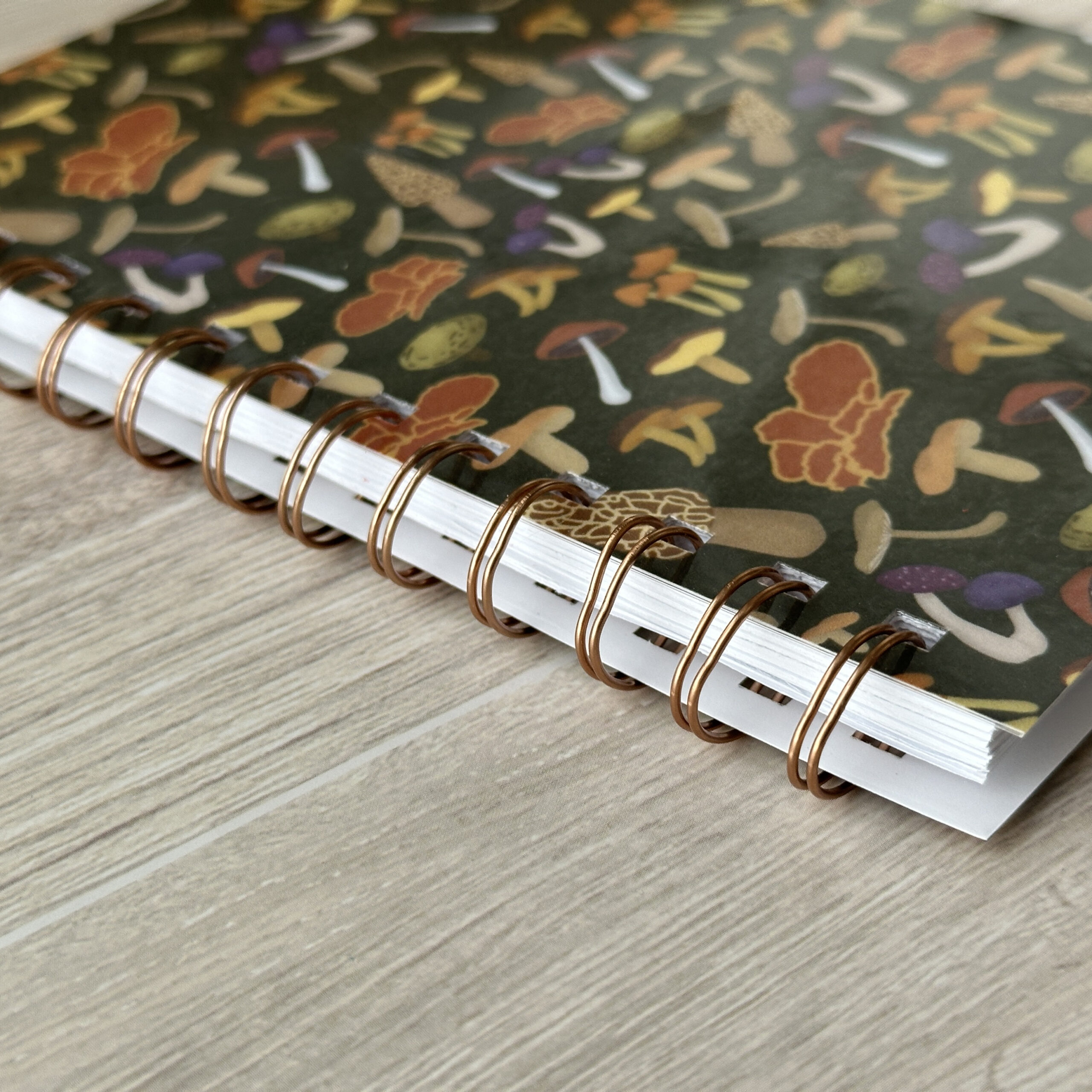 A close up view of the wire-o binding on a notebook with a mushroom patterned cover