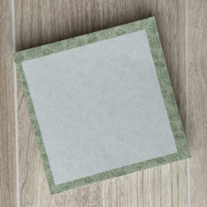 a square sticky note pad with tropical leaves and a light green background